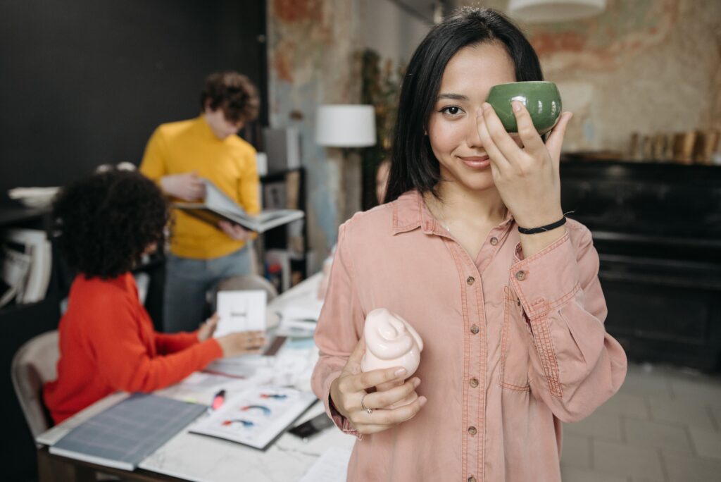 Young woman holding ceramic items, showcasing art and teamwork in a creative studio.